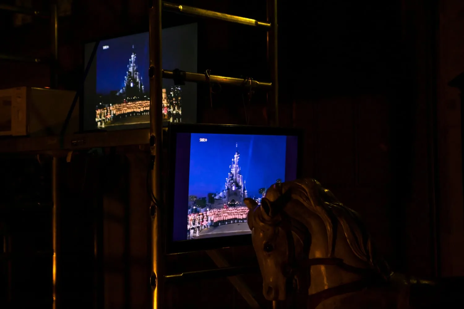 Alte Fernsehgeräte in einem Regal zeigen ein beleuchtetes Märchenschloss.