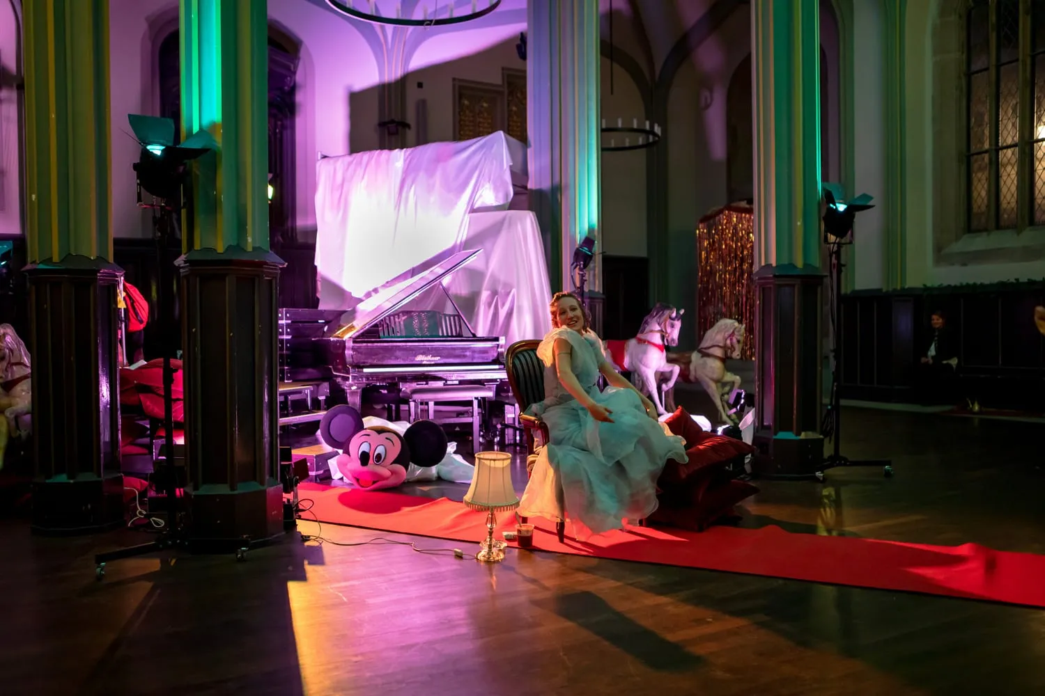 Blick in den Kirchenraum mit rotem Teppich, grün und magentafarben ausgeleuchtet.