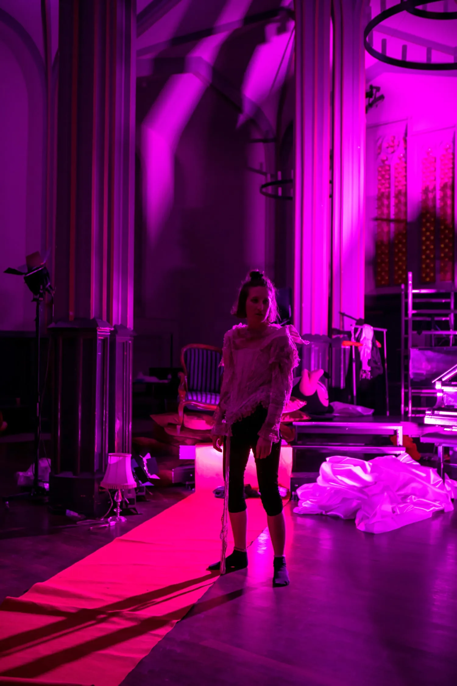 Eine Performerin auf rotem Teppich vor den Kirchenfenstern, magentafarbenes Licht.